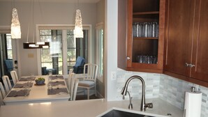 A modern kitchen with wooden cabinets, a stainless steel dishwasher, and a large island with seating. - Lagoonside Luxury • 5 min Walk to Beach • Pool, Hot Tub & Kiddie Pool (Hilton Head Island)