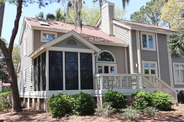 A two-story house with a covered porch, large windows, and a chimney.