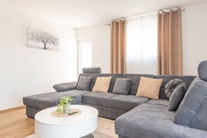 Una sala de estar moderna con un sofá modular, una mesa de centro redonda y un cuadro en la pared.