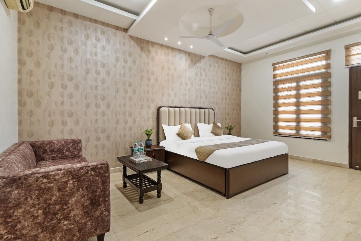 A bedroom with a bed, a nightstand, a chair, a ceiling fan, and a window with blinds.