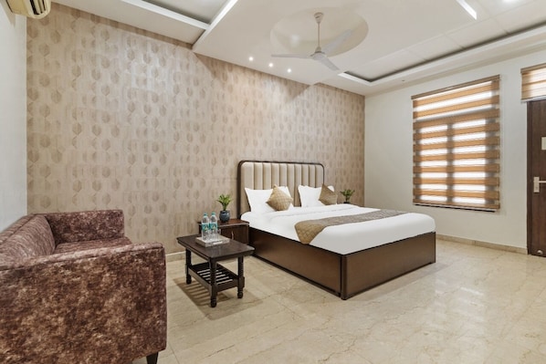 A bedroom with a bed, a nightstand, a chair, a ceiling fan, and a window with blinds.