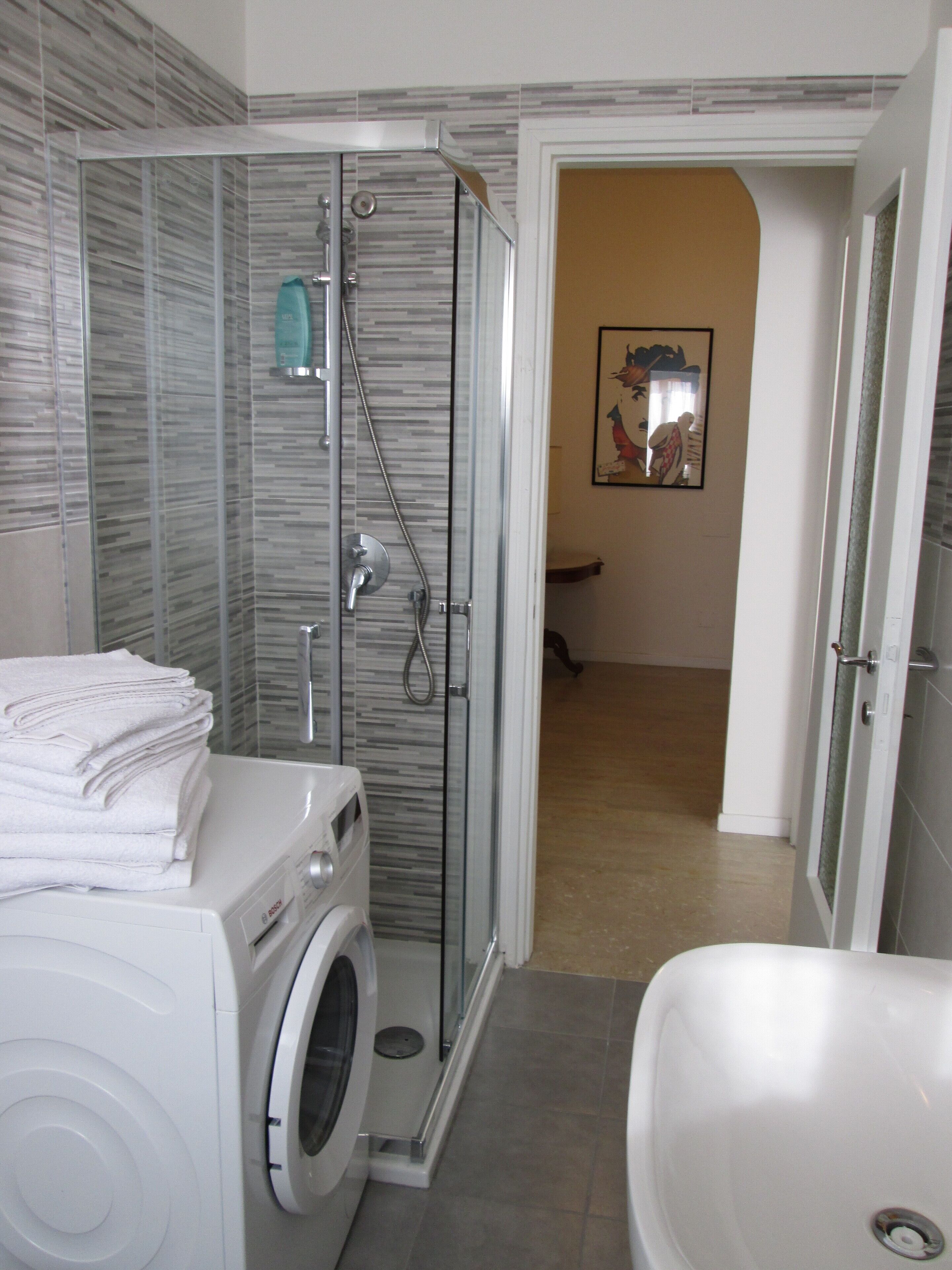 Un bagno con doccia vetro, lavatrice e vasca da bagno.