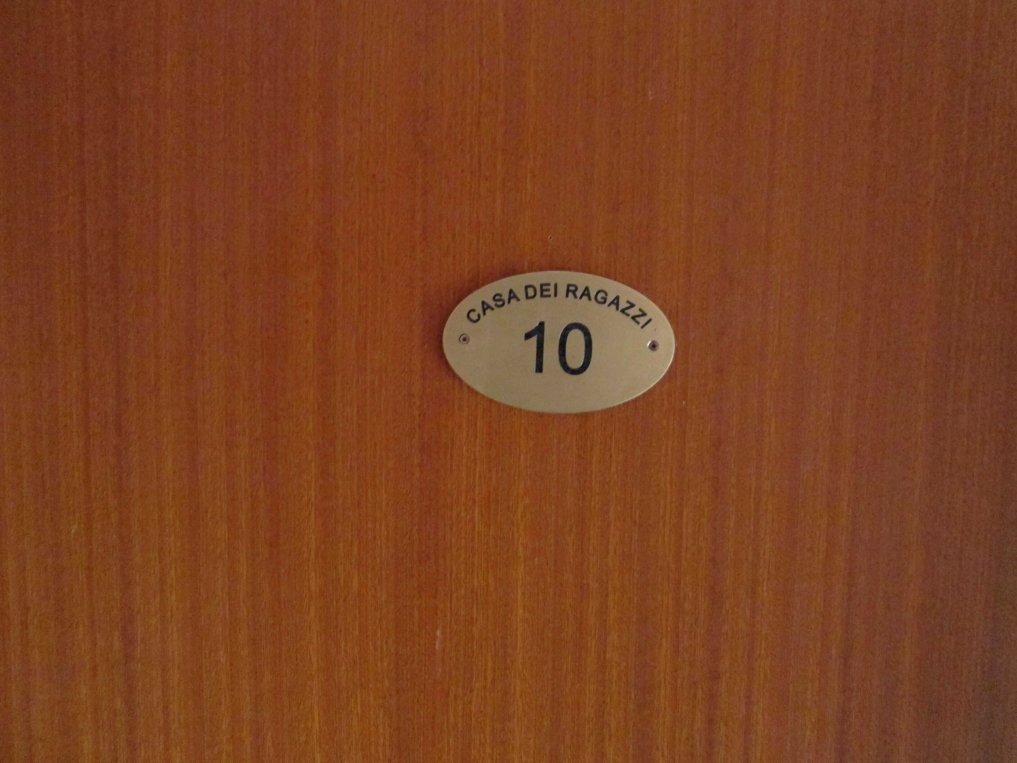 A wooden door with a brass plaque that reads "CASA DEI RAGAZZI 10".