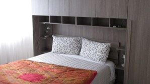 A bedroom with a bed, a bedside table, a lamp, and a ceiling fan.