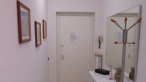 A hallway with a white door, a coat rack, and framed pictures on the wall.