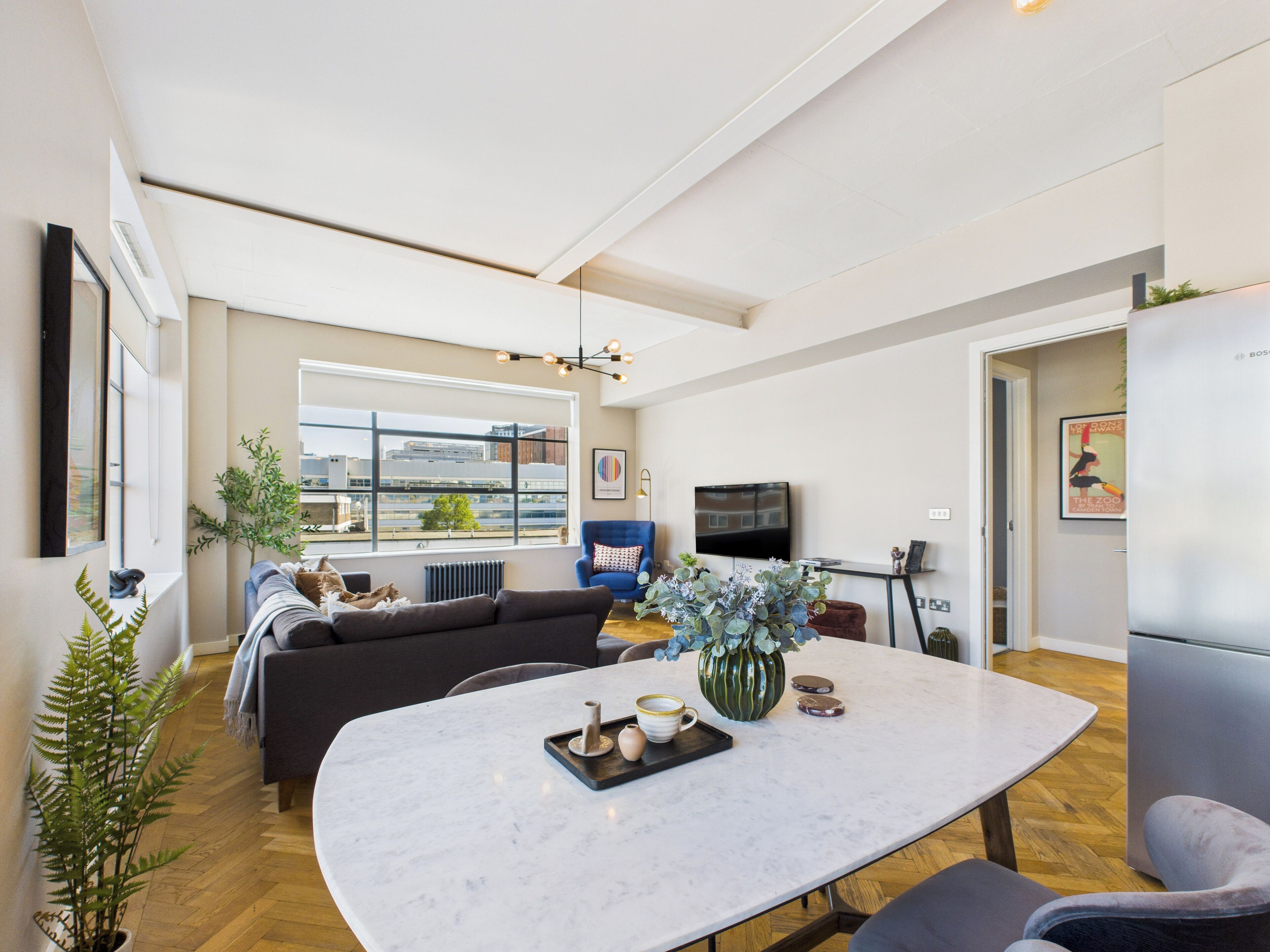 Una sala de estar moderna con un ventanal grande, un sofá, una mesa de comedor y un televisor.