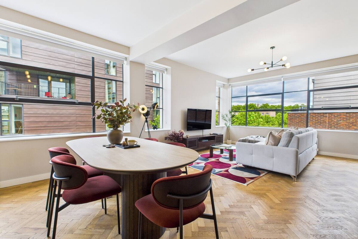 Un salón amplio con una gran mesa de comedor, varias sillas, un sofá y un televisor.