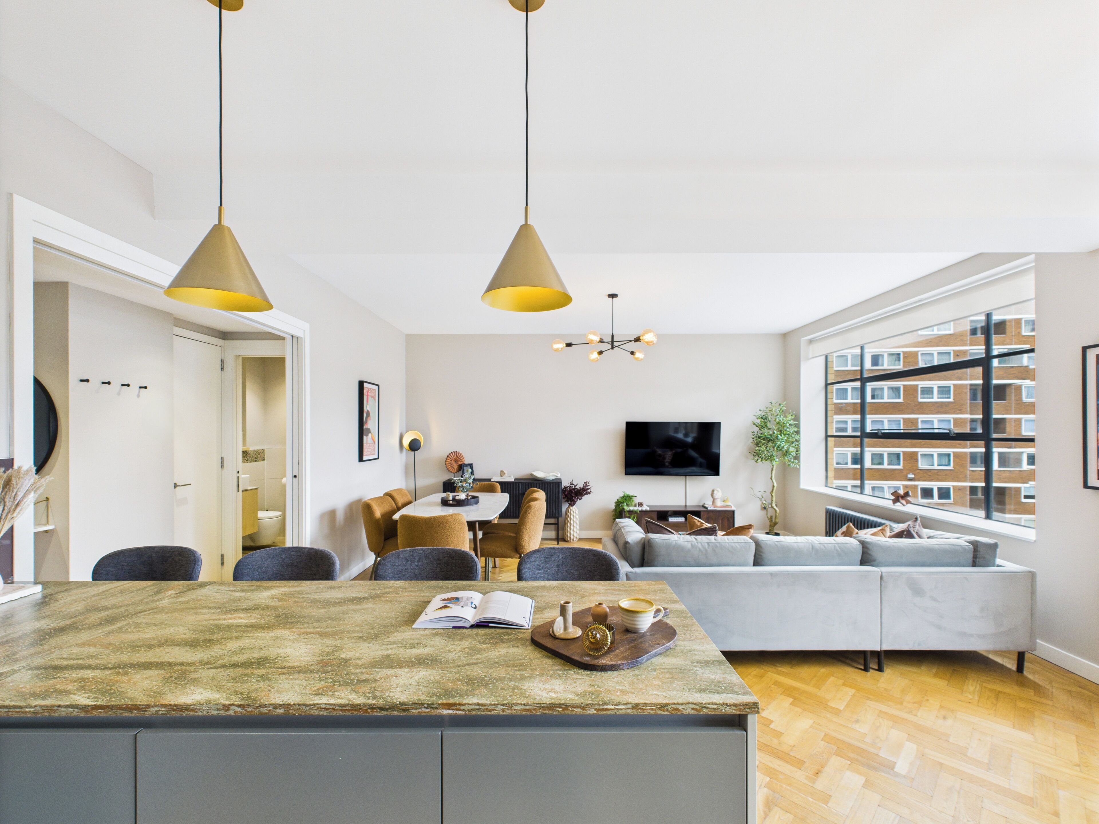 A modern living space with a central island, dining area, and seating.