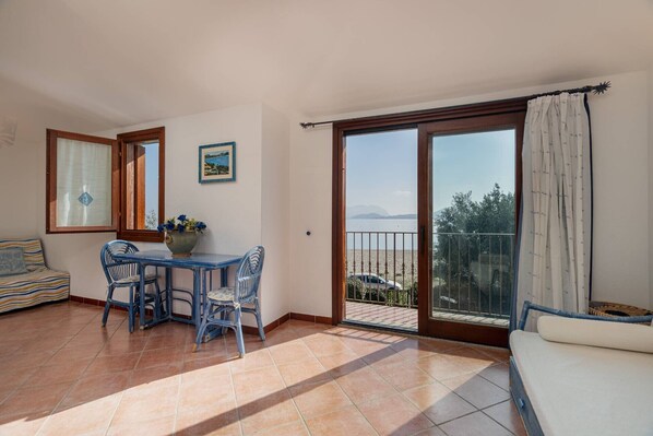 A balcony with a view of the sea, a dining area with a table and chairs, and a sofa.