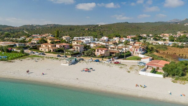 An aerial view of a coastal town with a sandy beach, houses, and a clear blue sea. - Loft delle brezze by Wonderful Italy (Olbia)