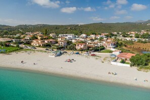 An aerial view of a coastal town with a sandy beach, houses, and a clear blue sea. - Loft delle brezze by Wonderful Italy (Olbia)
