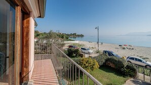 A balcony with a view of a beach, cars parked on the beach, and a clear sky. - Loft delle brezze by Wonderful Italy (Olbia)
