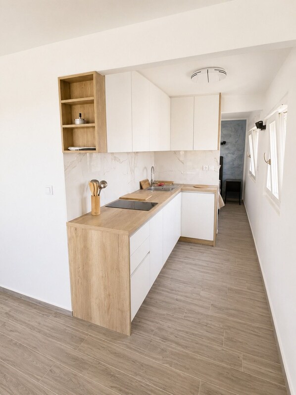 Una cocina moderna con armarios blancos, encimera de madera y salpicadero de mármol.