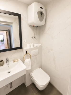 A modern bathroom with a white sink, a toilet, and a wall-mounted bidet. - Mediterraneo apartment A2 (Sukošan)