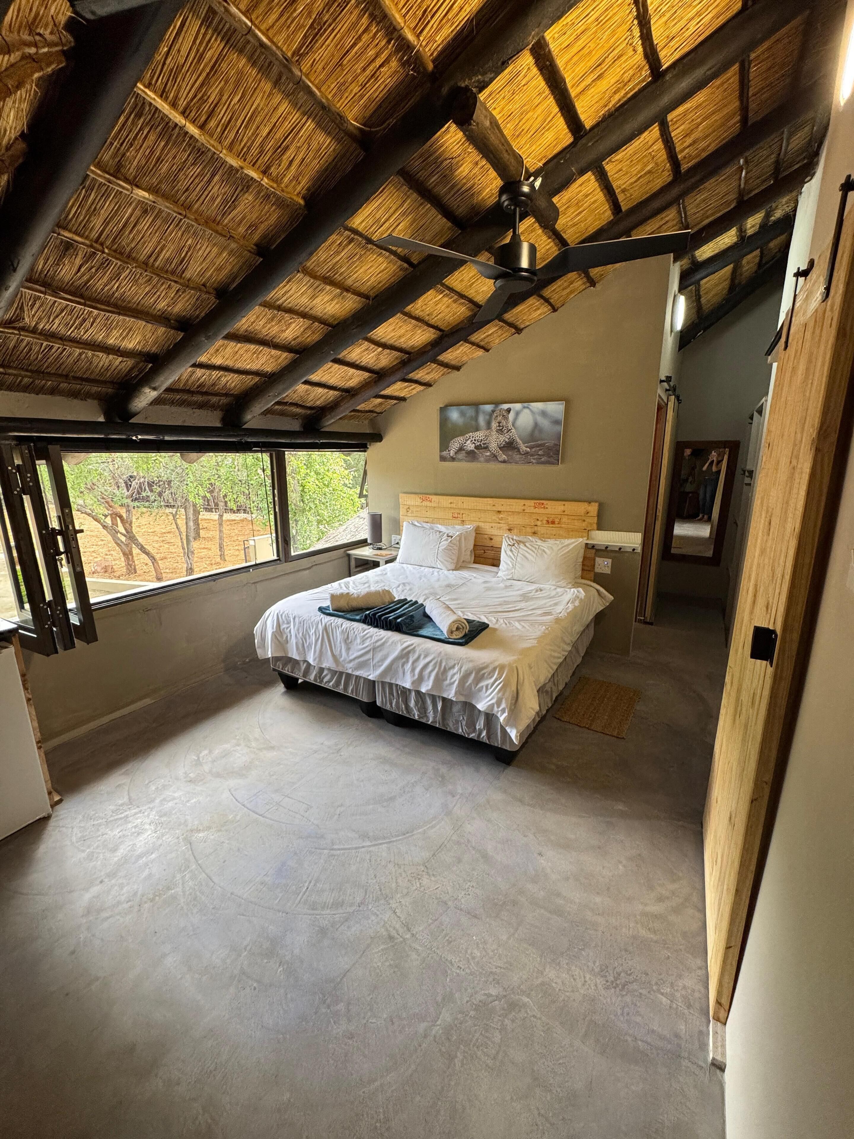 A spacious bedroom with a large bed, a ceiling fan, and a view of the outdoors.