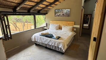 A spacious bedroom with a large bed, a ceiling fan, and a view of the outdoors.