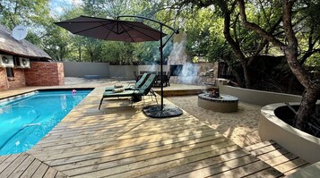 Una piscina al aire libre, sombrillas, sillones reclinables de piscina