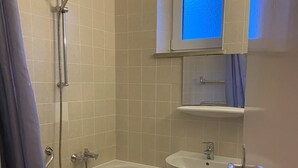 Un baño con bañera, lavabo y ducha.