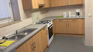 Una cocina con armarios de madera, encimera de granito, estufa, fregadero y cafetera.