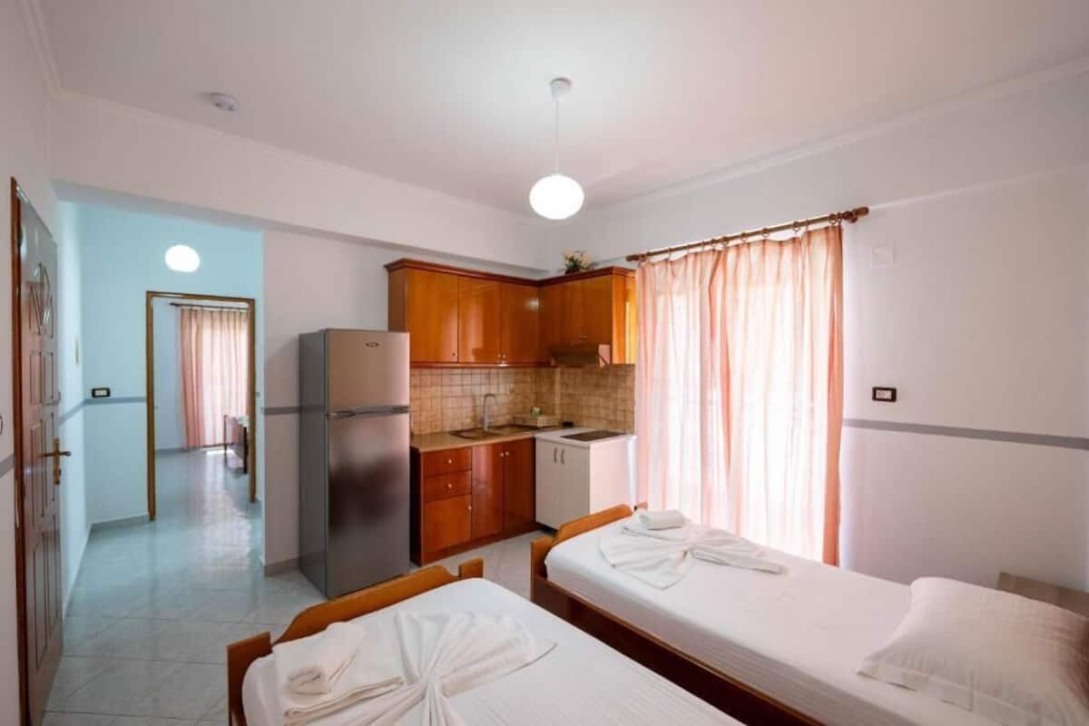Una habitación con dos camas, kitchenette y baño.