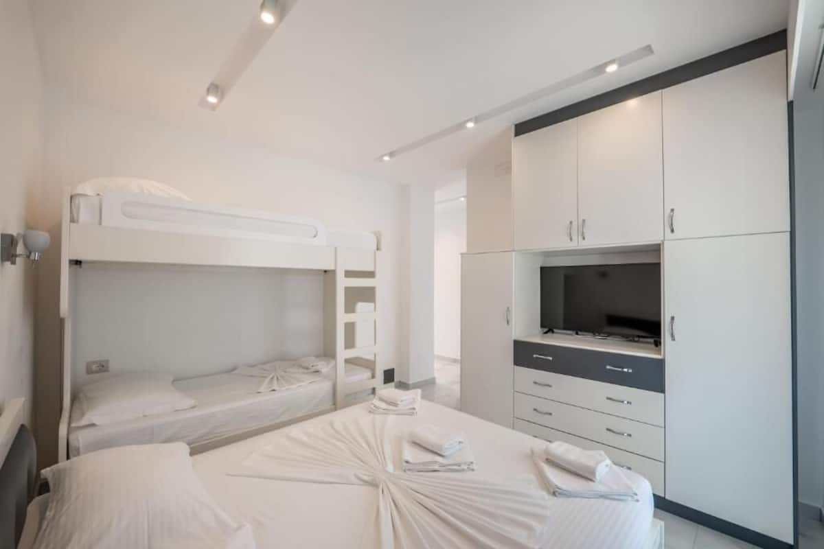 Una habitación de hotel moderna con literas, televisión de pantalla plana y minibar.
