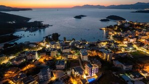 Une ville côtière au crépuscule, avec des bâtiments le long du front de mer, un port de plaisance et des bateaux.