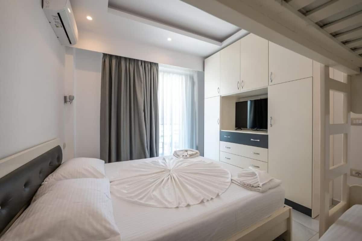 Una habitación de hotel con cama, armario, televisor y aire acondicionado.