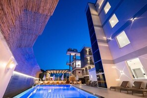 A modern hotel with a pool area, lounge chairs, and a multi-story building with balconies. - Mario Apartments  (Ksamil)