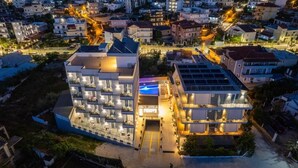 Een modern hotel met meerdere verdiepingen, een centrale ingang en een terras op het dak.