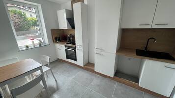 Eine moderne Küche mit weißen Schränken, einer Holzausziehtafel und einem eingebauten Backofen.