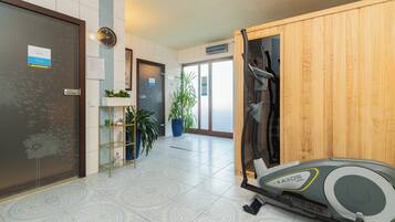 Un vestíbulo de hotel con mostrador de recepción, un reloj, una planta y una cinta de correr.