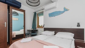 Habitación de hotel con cama, escritorio, silla, armario y una pared decorada con un mural de ballena.