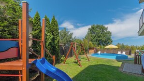 Un parque infantil con tobogán, columpios y piscina.