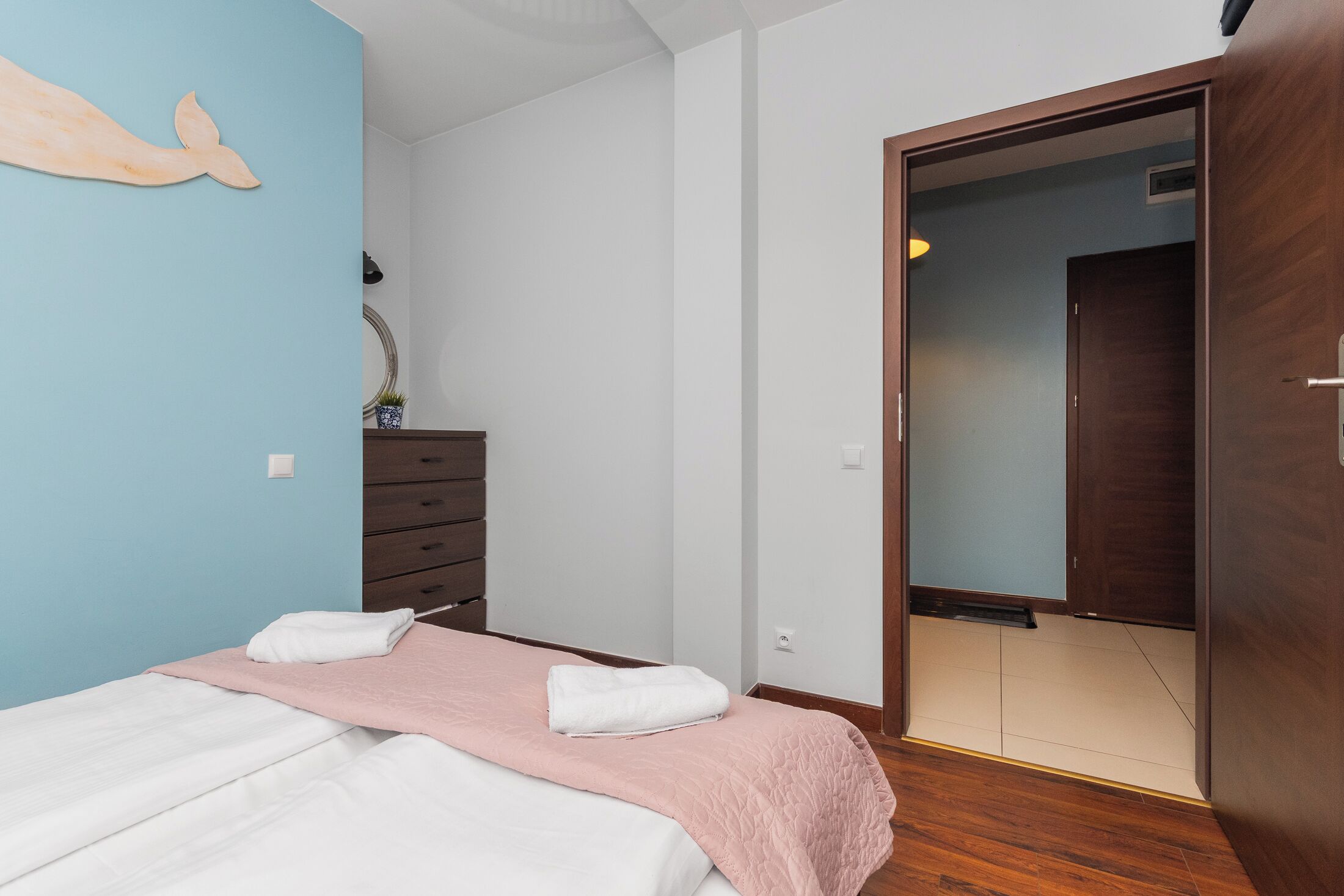 A bedroom with a bed, a dresser, a wardrobe, and a wall decoration.