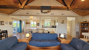 A spacious living area with a high ceiling, wooden beams, and a central seating area with blue upholstered sofas. - 5-bedroom house in tranquil Corolla North Carolina OBX 4x4 Carova (Corolla)