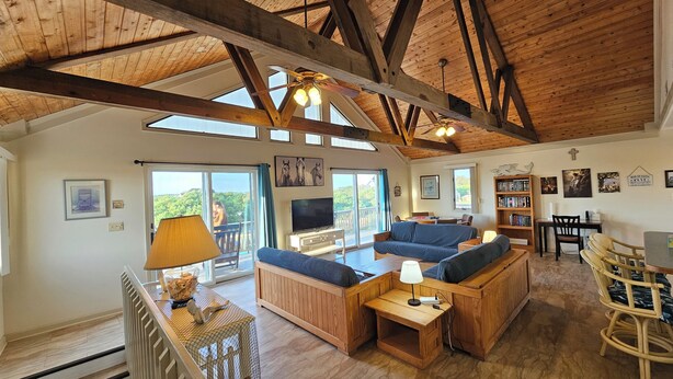 A spacious living area with wooden beams, a sofa set, a TV, and a bookshelf. - 5-bedroom house in tranquil Corolla North Carolina OBX 4x4 Carova (Corolla)