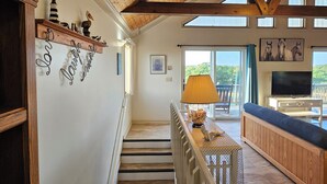 A wooden staircase with a view of a living area, a TV, and a dining table with chairs. - 5-bedroom house in tranquil Corolla North Carolina OBX 4x4 Carova (Corolla)