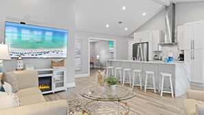 A modern living room with a fireplace, a TV, and a dining area with bar stools.