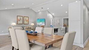 A modern dining area with a wooden table, beige chairs, and a large painting on the wall.