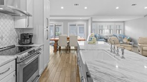 A modern kitchen with a large island, built-in oven, and white cabinetry.