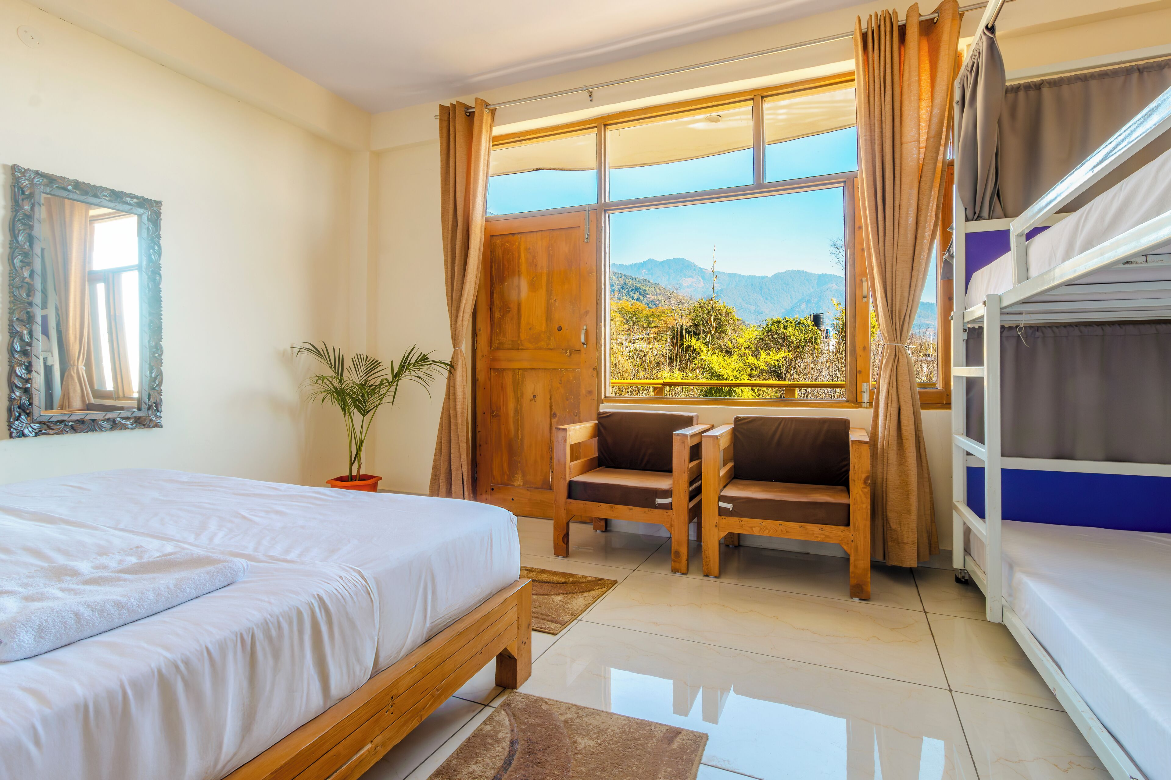 Una habitación con cama, ventana con cortinas, escritorio y literas.