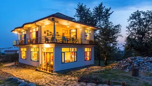 A two-story house with a balcony, large windows, and a stone pathway leading to the entrance. - Dormigo  (Baijnath)