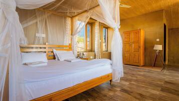 A wooden four-poster bed with white linens, a wooden nightstand, and a wooden wardrobe in a room with wooden flooring and a wooden ceiling.