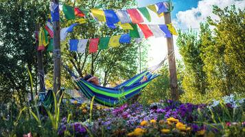 A hammock in a lush garden with colorful prayer flags.
