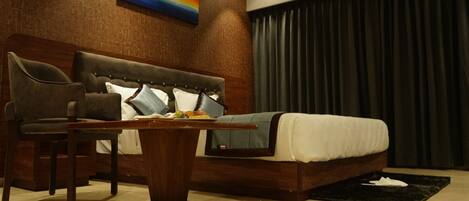 A modern bedroom with a wooden bed frame, a headboard, a dining table, and two chairs.