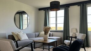 A modern living room with a grey sofa, a round mirror, a coffee table, and a black armchair. - Heated pool, House in the heart of the vineyards (Puisseguin)