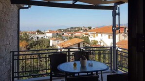 A balcony with a table and chairs, overlooking a residential area with houses and a clear sky.