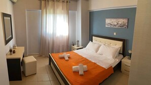 A hotel room with a bed, a desk, a chair, a nightstand, a mirror, and a painting on the wall.
