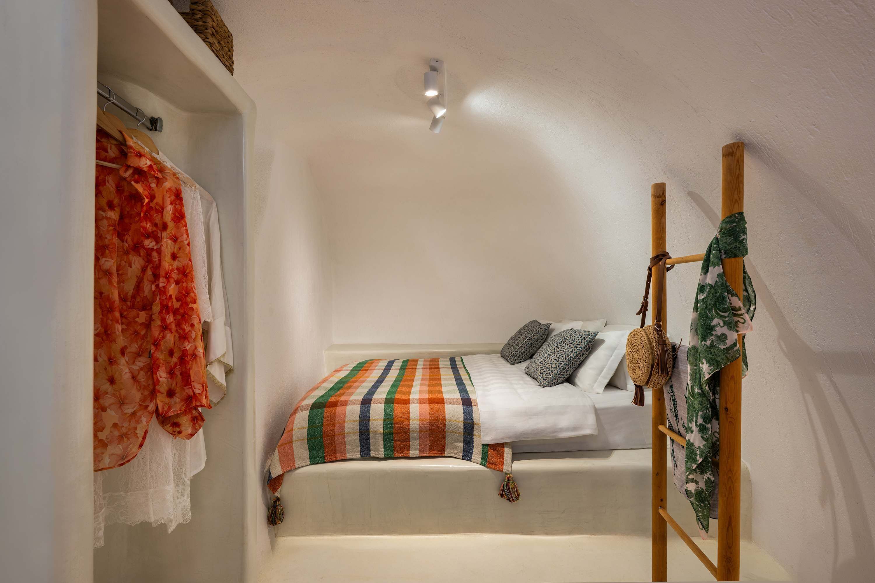 A small, cozy bedroom with a single bed, a wooden ladder, and a hanging basket.