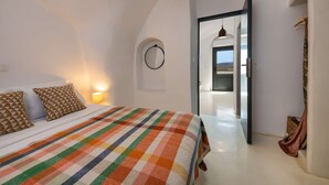 A bedroom with a large bed, a view of the outside, and a door leading to another room. - Amphora Selene Seaview Getaway in Akrotiri (Santorini)